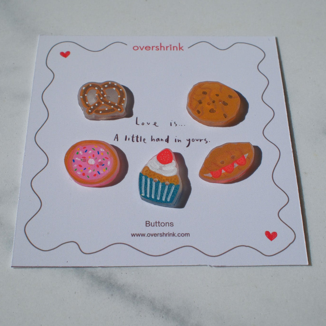 Card with illustrations of buttons shaped like donuts, pretzels, cookies, and a cupcake on a white background.