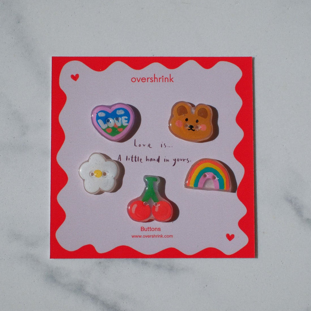 Set of colorful pins on a red card with 'overbrink' branding on a marble surface.