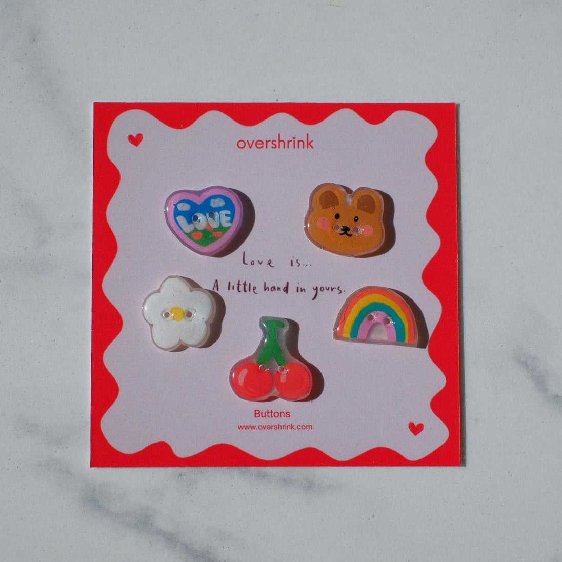 Set of colorful pins on a red card with 'overbrink' branding on a marble surface.