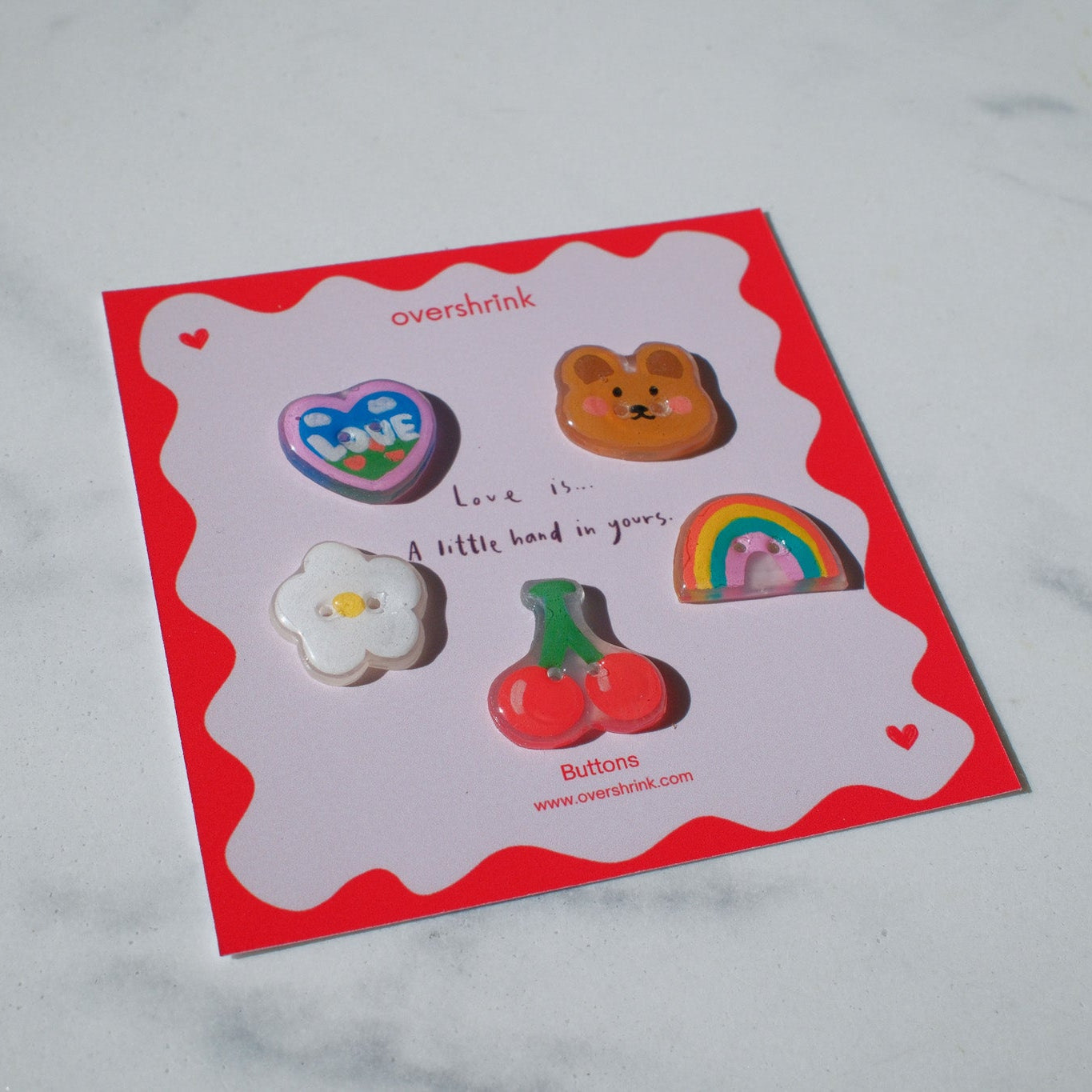 Set of colorful buttons on a branded card with a red border.