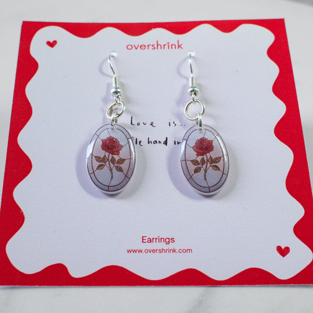 Pair of earrings on a red and white card with 'overshrink' branding.