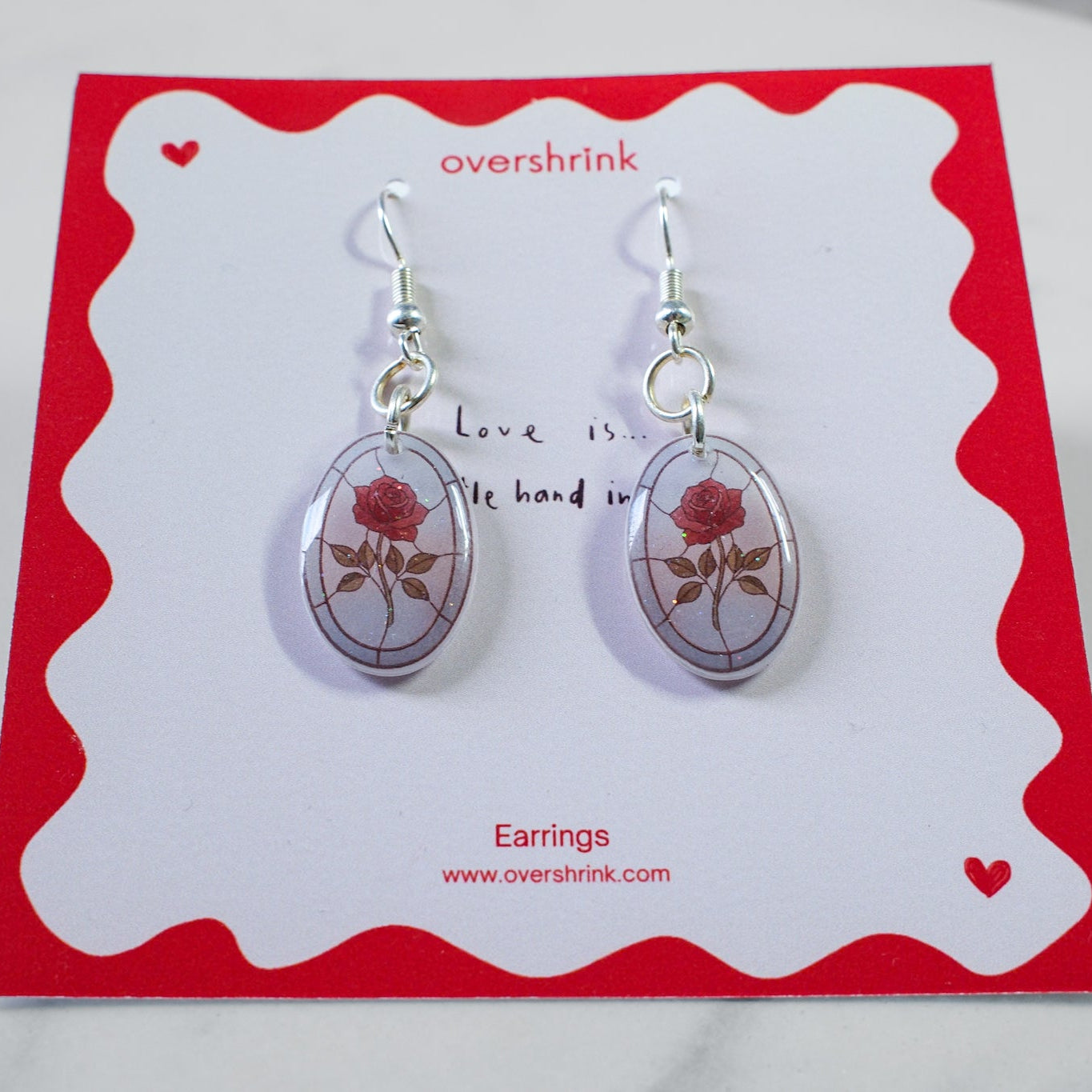 Pair of earrings on a red and white card with 'overshrink' branding.