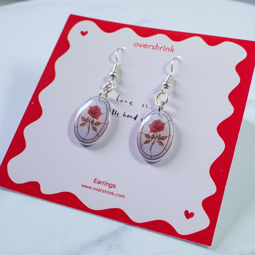 Pair of earrings on a red and white card with 'overshrink' branding.