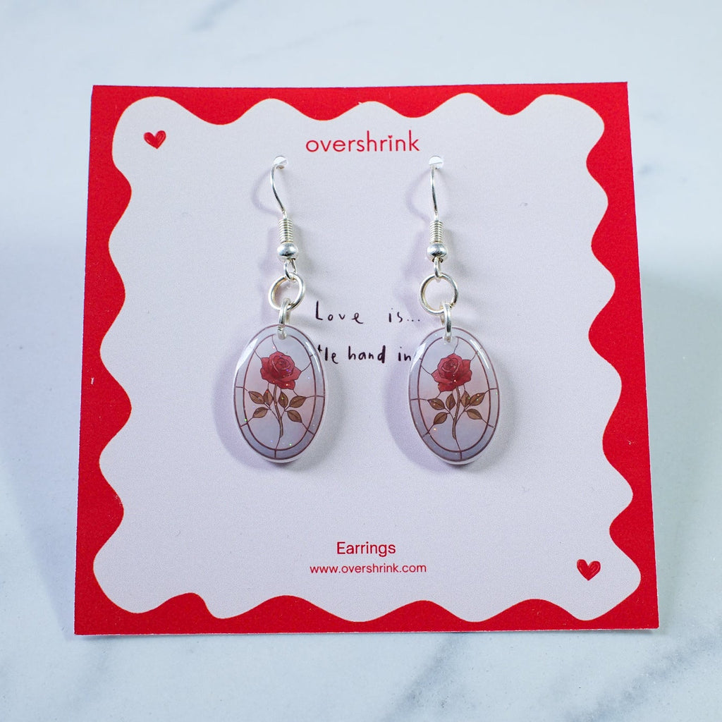 Pair of earrings on a 'overshrink' branded card with a red border.