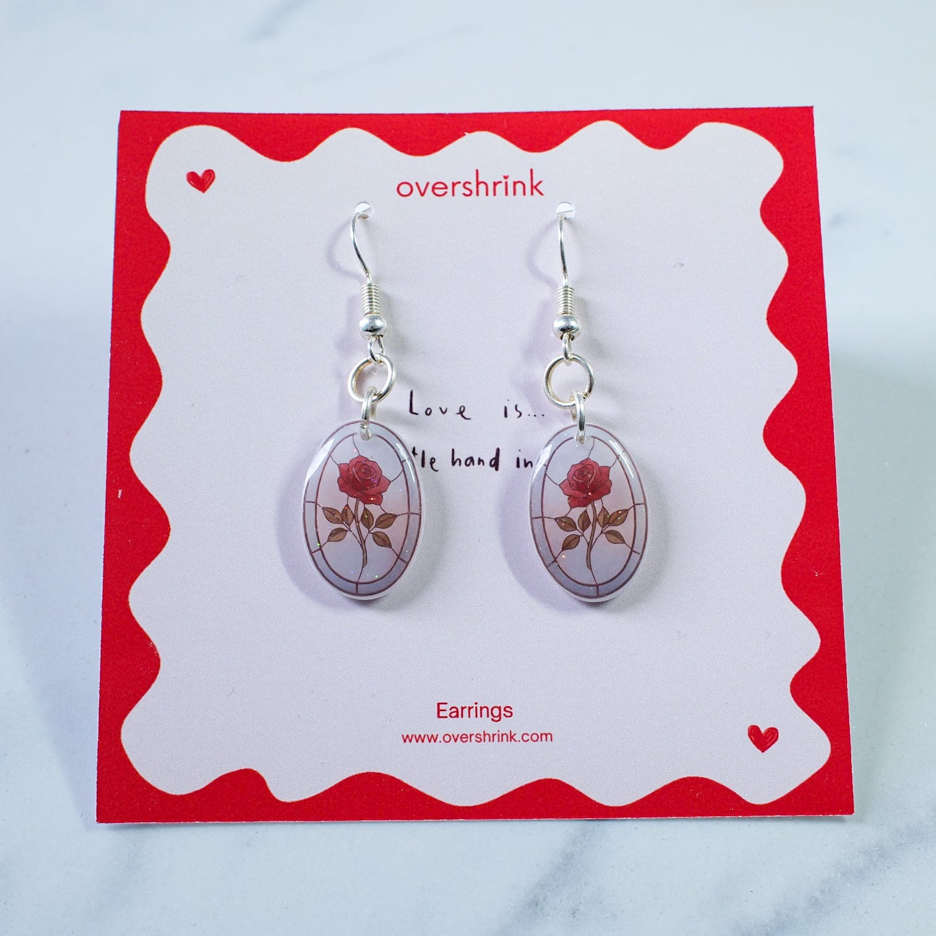 Pair of earrings on a 'overshrink' branded card with a red border.