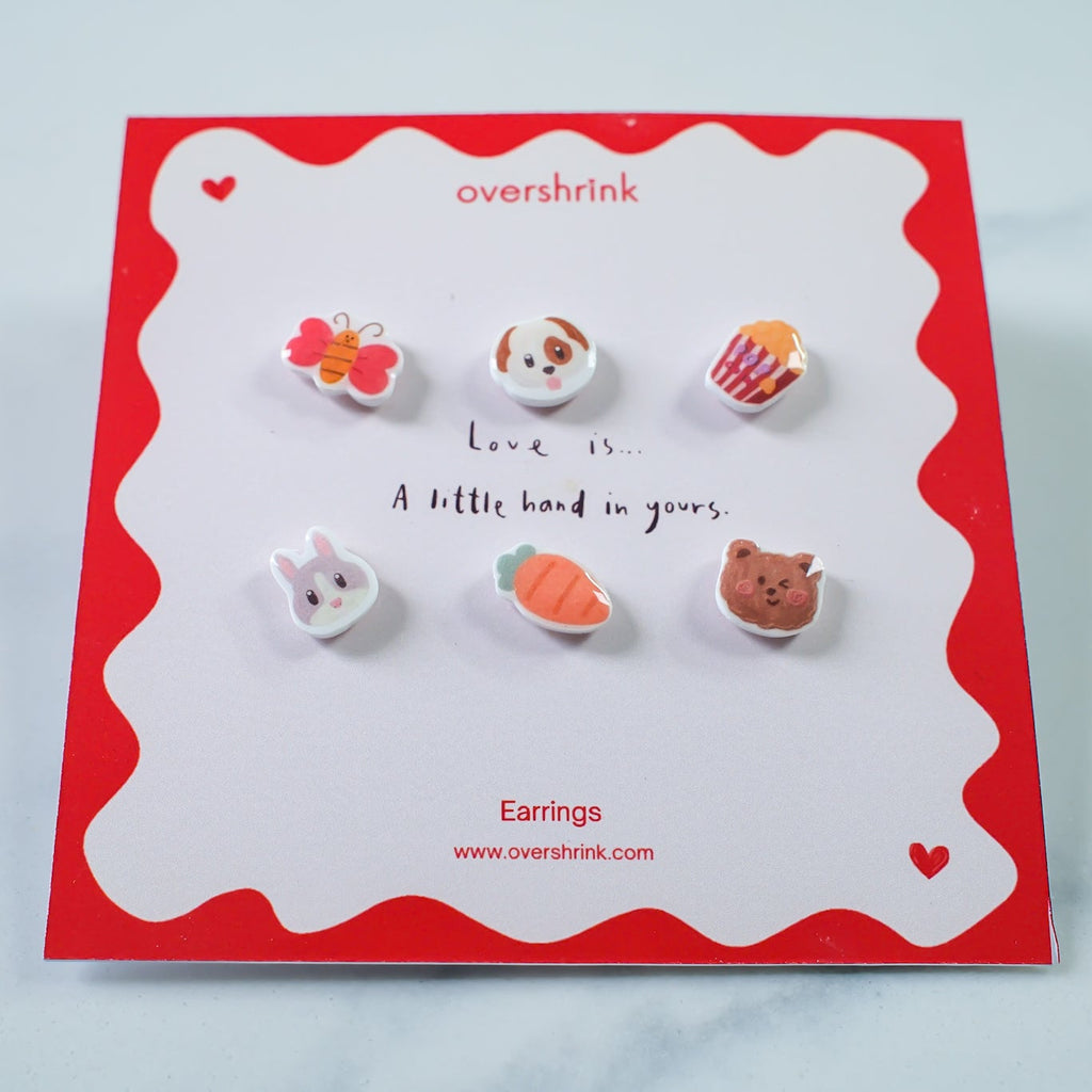 Set of small animal-themed earrings on a branded card with a red border.