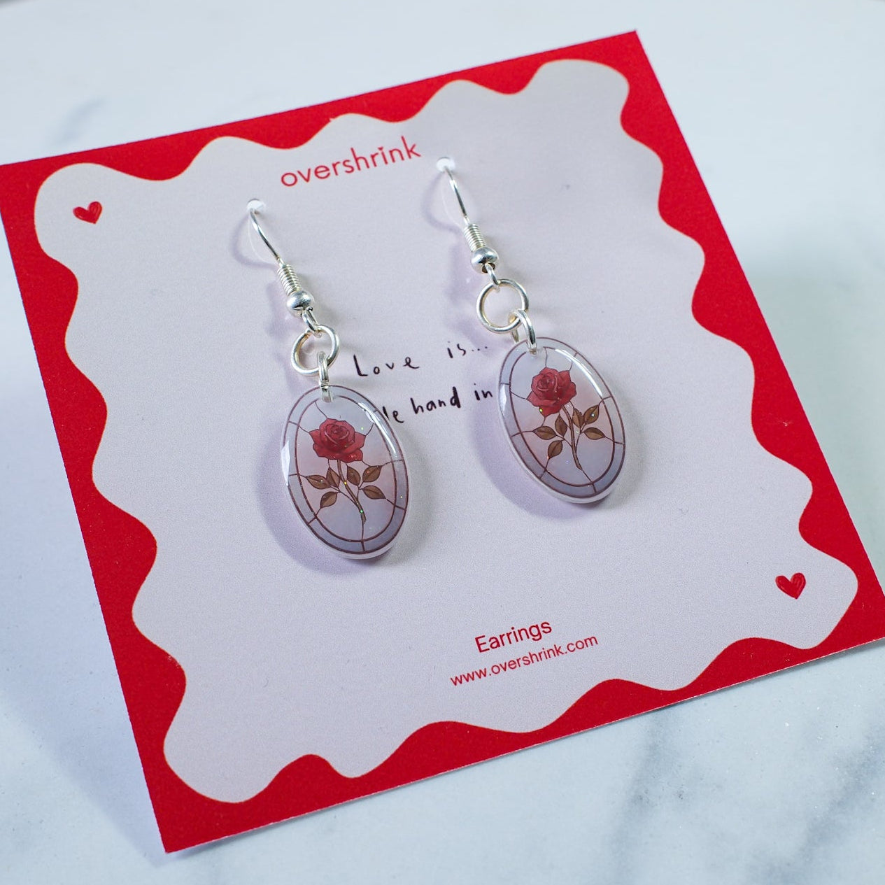 Pair of earrings on a branded card with a red border