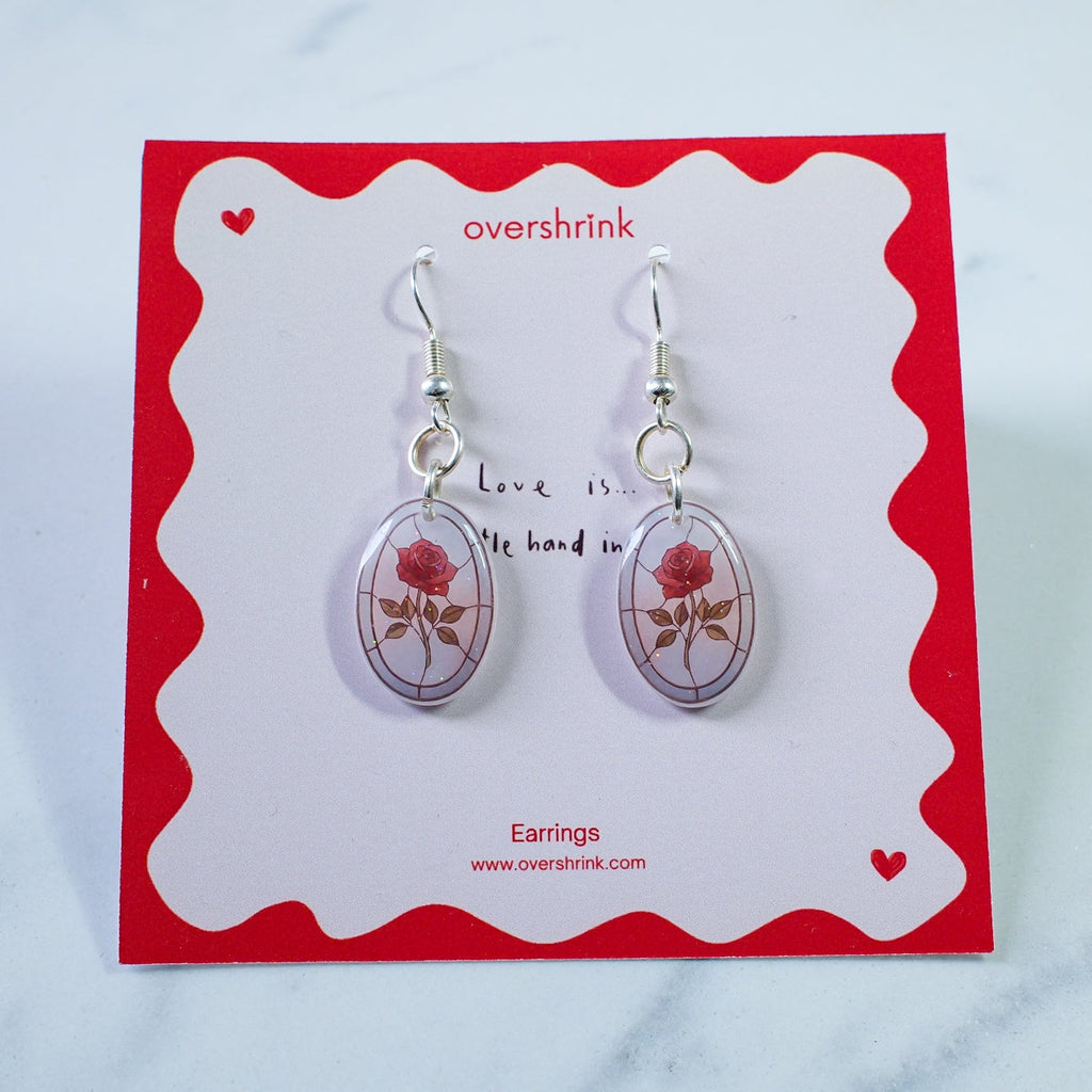 Pair of earrings on a red and white card with 'overshrink' branding.