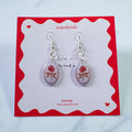 Pair of earrings on a red and white card with 'overshrink' branding.