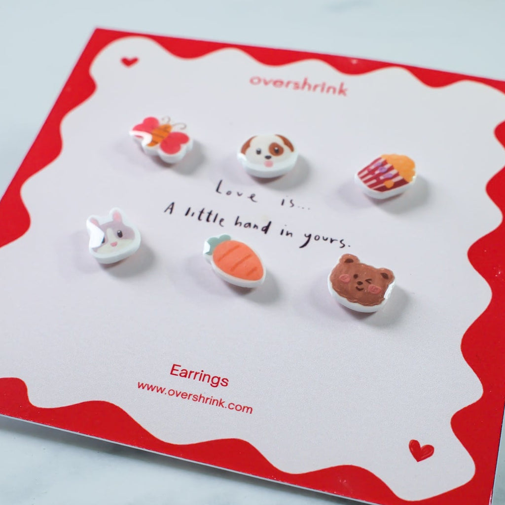 Set of small animal-shaped earrings on a branded card with a red border.